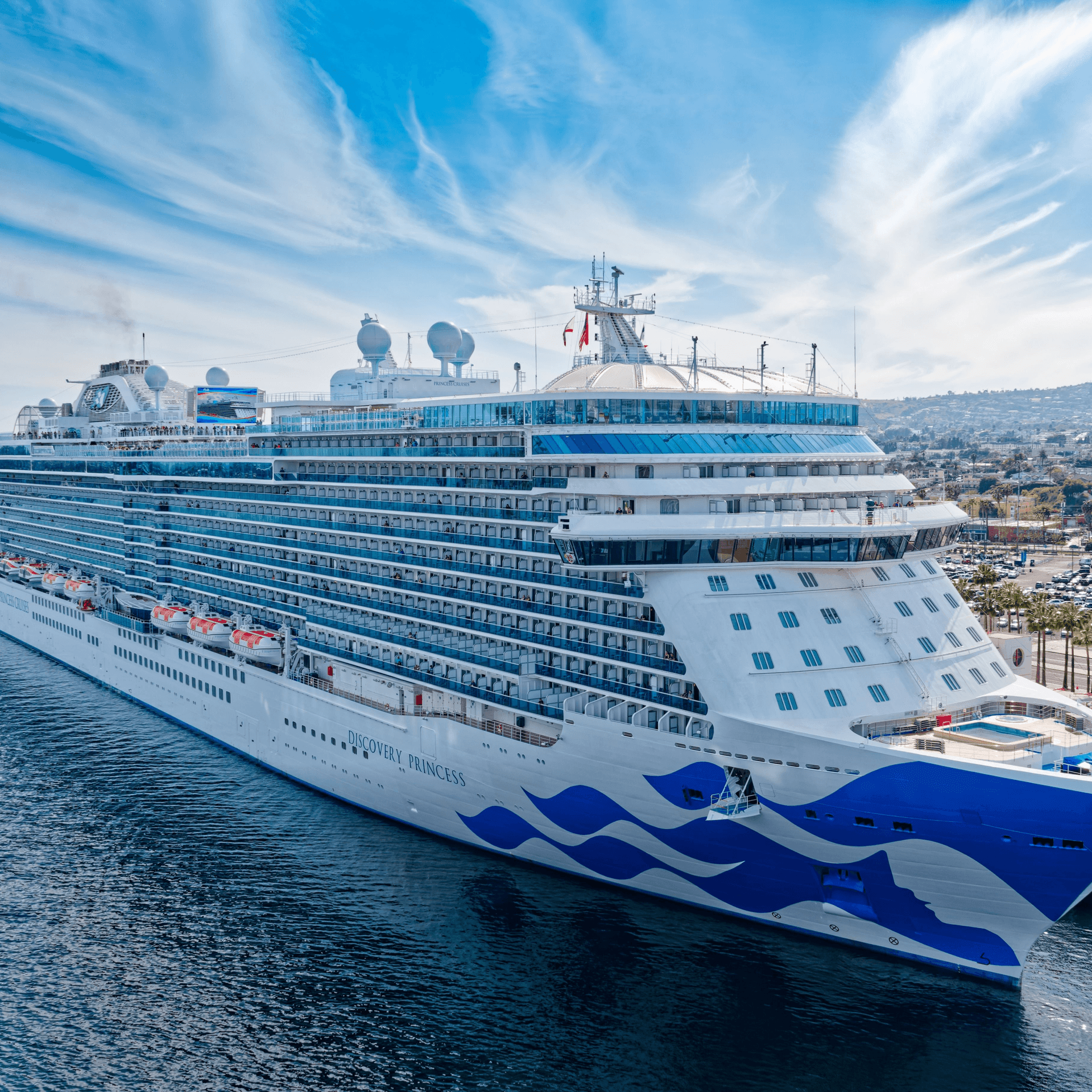 Large cruise ship docked at a port with a clear blue sky in the background.